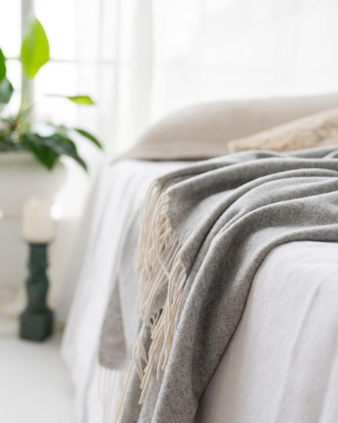 Cashmere blanket on white linen in a light filled bedroom
