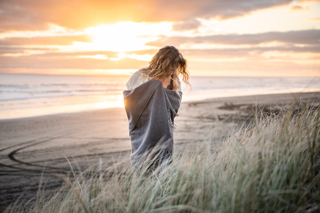 Cashmere wrap around a blonde haired women at sunset on a west coast beach of New Zealand