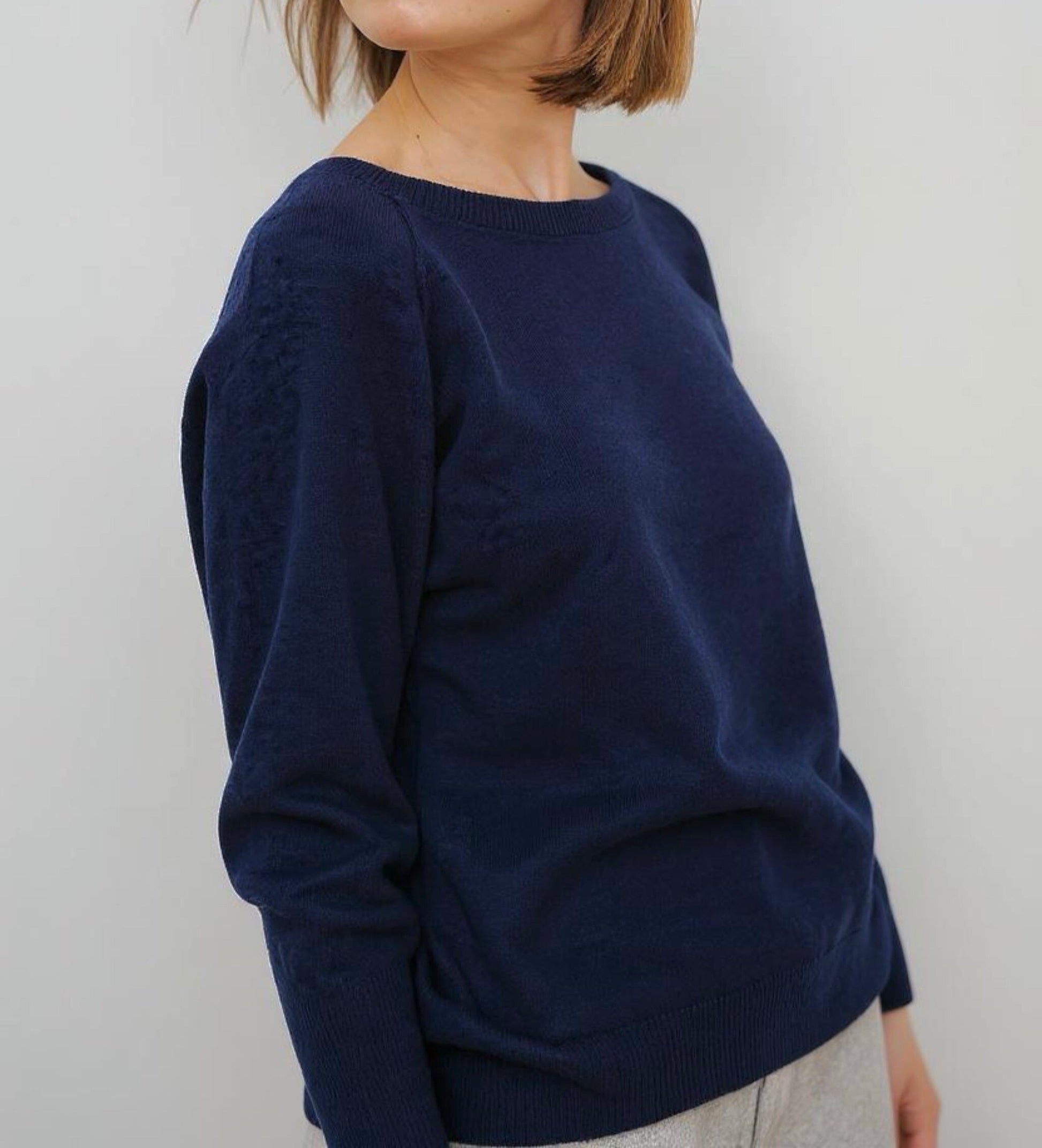 Woman wearing a navy blue sweater against a plain background