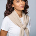 Woman wearing a beige scarf against a gray background