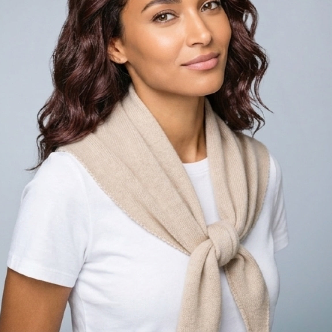 Woman wearing a beige scarf against a gray background