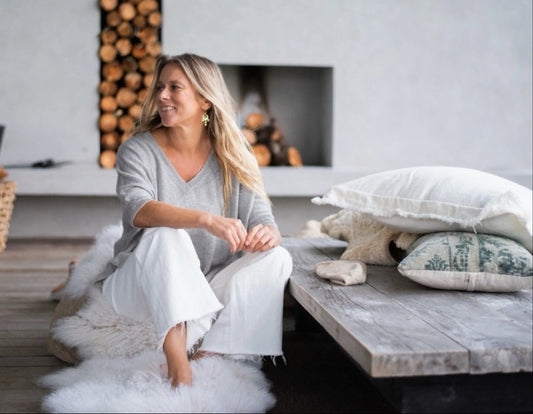 Woman wearing cashmere v-neck spring cashmere top sitting by outdoor fireplace and decking.