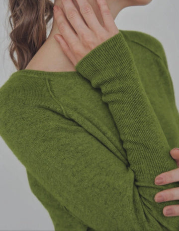 Person wearing a green sweater with a neutral background