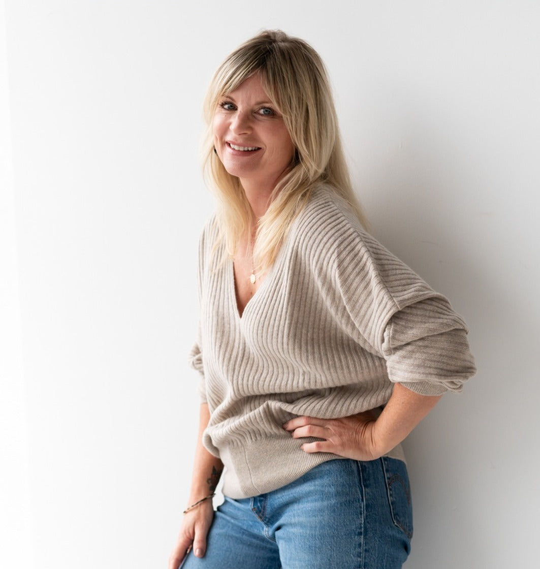 Beautiful blonde woman wearing cashmere jumper and blue jeans with hand on hip
